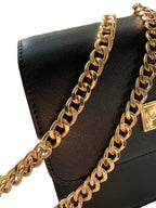 Black handbag with a gold chain strap on a white background
